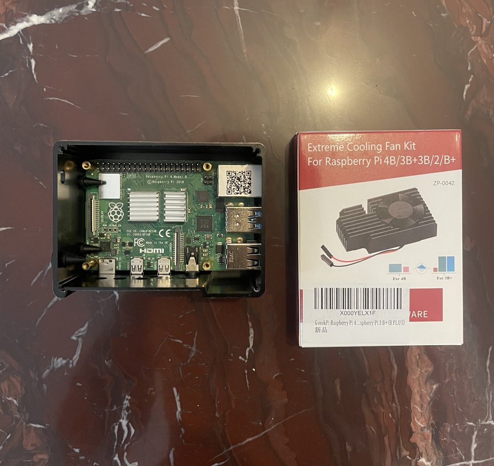 Raspberry Pi 4 board sitting in the open case next to the unopened Extreme Cooling Fan Kit box