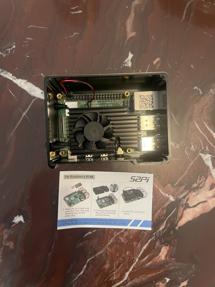 Fan and heatsink mounted onto the Pi board inside the case, with the manufacturer's 3-step instruction card shown below it