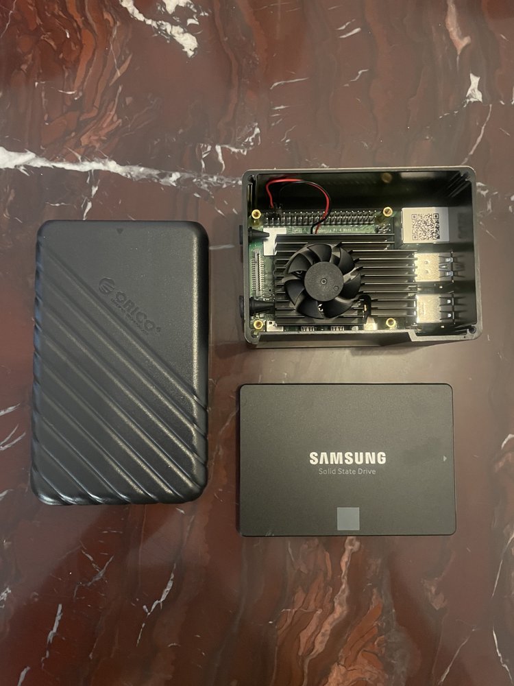 Samsung SSD, ORICO enclosure, and the fan-equipped Pi case laid out side by side before assembly